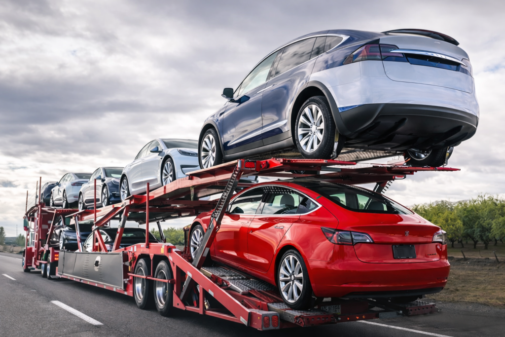 Multi-level car carrier trailer transporting new electric and modern vehicles on a highway, representing international vehicle logistics and auto export services.
